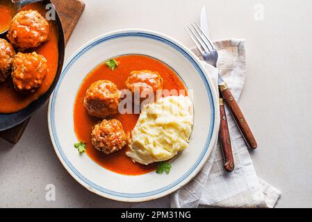 Gebratene Fleischbällchen, geschmort in Tomatensauce, serviert mit Kartoffelpüree auf einem weißen Tisch. Ich esse mit Rind gebratene Fleischbällchen in Tomatensoße. Stockfoto