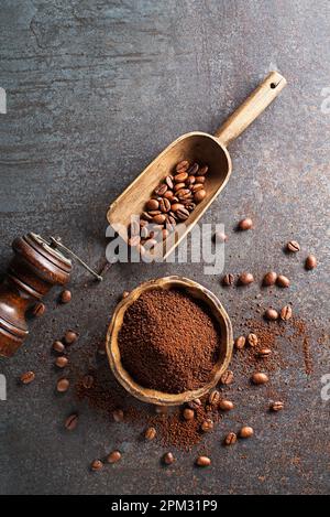 Kaffeebohnen und frisch gemahlenes Kaffeepulver auf grauem Steinhintergrund – Nahaufnahme Stockfoto