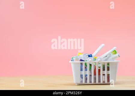 Vollständiger Warenkorb auf Holztisch, Speisen und Lebensmittel im Warenkorb auf pinkfarbenem Hintergrund, Kopierbereich Stockfoto