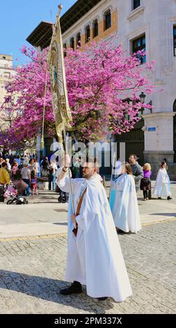 Ostersonntagsumzug mit Teilnehmer in langen Bademänteln mit einem Kirchenbanner Santander Cantabria Spanien, 9. April 2023 Stockfoto