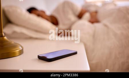Mann Zu Hause Schläft Im Bett Und Der Alarm Geht Auf Dem Mobiltelefon Aus Stockfoto