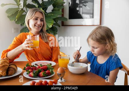 Mutter und Tochter frühstücken zu Hause. Ich sitze am Tisch in der Küche Stockfoto