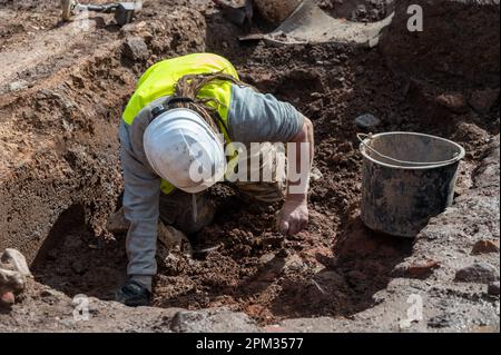 Trier, Deutschland. 11. April 2023. Ein Mann gräbt an einer archäologischen Stätte, wo ein 1,20 Meter langes Kalksteinrelief von Cautes, Begleiter des römischen gottes des Lichts Mithras, gefunden wurde. (Zu dpa 'spektakuläre Entdeckung' - Kultstätte mit römischem Relief entdeckt) Kredit: Harald Tittel/dpa/Alamy Live News Stockfoto