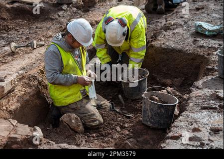 Trier, Deutschland. 11. April 2023. Ein Mann packt eine geborgene Münze an einer archäologischen Stätte ein, wo auch ein 1,20 Meter langes Kalksteinrelief von Cautes, Begleiter des römischen gottes des Lichts Mithras, gefunden wurde. (Zu dpa 'spektakuläre Entdeckung' - Kultstätte mit römischem Relief entdeckt) Kredit: Harald Tittel/dpa/Alamy Live News Stockfoto