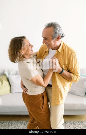 Viel Spaß beim Tanzen. Glücklicher charmanter älterer Mann und Frau, der romantische Momente genießt, während er Walzer im Wohnzimmer tanzt Stockfoto