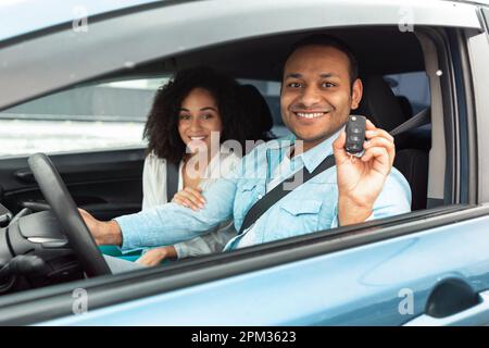 Glückliches Nahöstliches Paar, Das Den Neuen Autoschlüssel Zeigt, Das Drinnen Sitzt Stockfoto