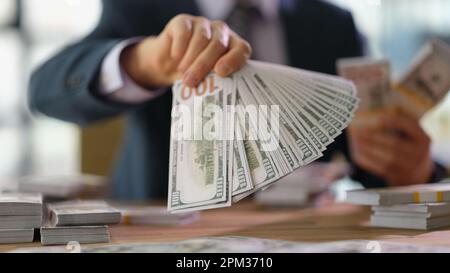 Ein Geschäftsmann, der eine Menge Dollar-Banknoten in der Fächeraufnahme hält Stockfoto