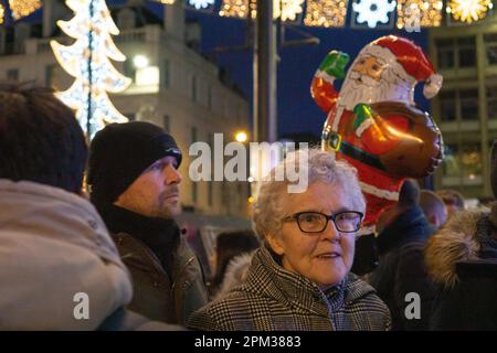 Eine lächelnde Seniorin, die den Glasgow Christmas Market in Schottland genießt Stockfoto