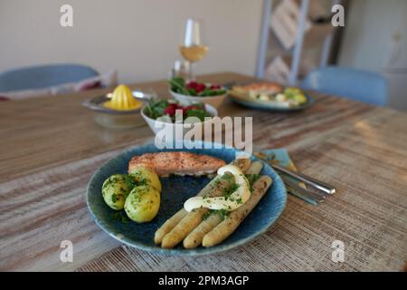 Eine Nahaufnahme aus gedämpften Kartoffeln, flämischem Spargel und gebackenem Lachs auf einem Teller Stockfoto