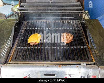 Hamburger und Cheeseburger Grillen auf einem Gasgrill im Freien in Montgomery Alabama, USA. Stockfoto