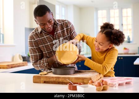 Familienfoto Mit Vater Und Tochter Backen Zu Hause In Der Küche, Kuchenmischung In Die Dose Gießen Stockfoto