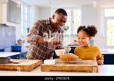 Familienfoto Mit Vater Und Tochter Backen In Der Küche Dekorationskuchen Mit Glasur Stockfoto