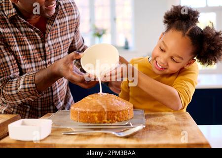 Familienfoto Mit Vater Und Tochter Backen In Der Küche Dekorationskuchen Mit Glasur Stockfoto