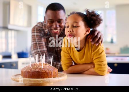 Vater Und Tochter In Home In Kitchen Feiern Kerzen Auf Hausgemachtem Geburtstagskuchen Stockfoto