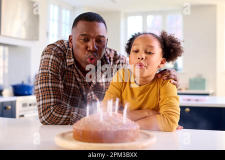 Vater Und Tochter In Home In Kitchen Feiern Kerzen Auf Hausgemachtem Geburtstagskuchen Stockfoto