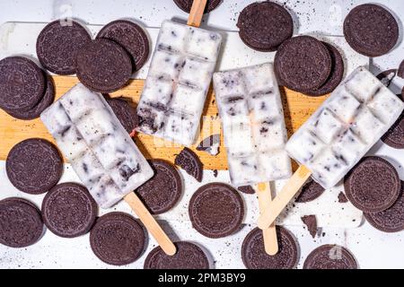 Sahne und Kekse, Eis am Stiel, Vanilleeis, Lollipops mit Schokoladen-zerdrückten Keksen, mit vielen Keksen auf dem Küchentisch hinten Stockfoto