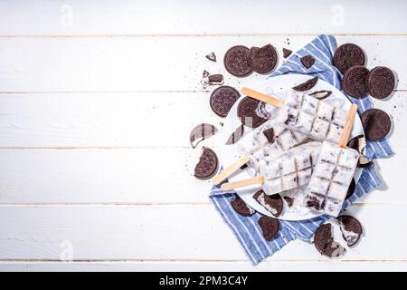 Sahne und Kekse, Eis am Stiel, Vanilleeis, Lollipops mit Schokoladen-zerdrückten Keksen, mit vielen Keksen auf dem Küchentisch hinten Stockfoto