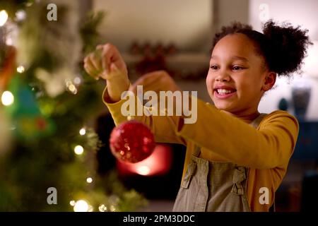 Aufgeregtes Mädchen Zu Hause In Weihnachtsdekoration Am Baum Stockfoto