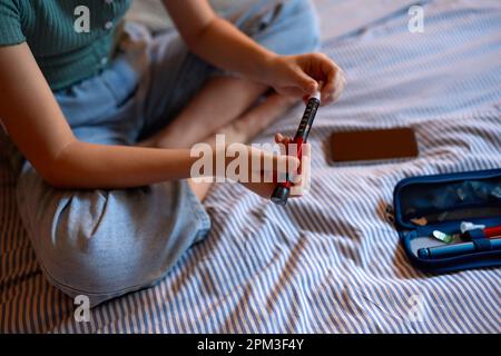 Nahaufnahme Eines Jungen Diabetikers, Das Zu Hause Im Bett Sitzt, Mit Einem Set Zur Überprüfung Des Insulinspiegels Stockfoto