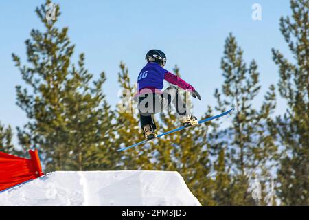 Weibliche Snowboarderinnen springen in Snowboardwettkämpfen, Wintersport Stockfoto