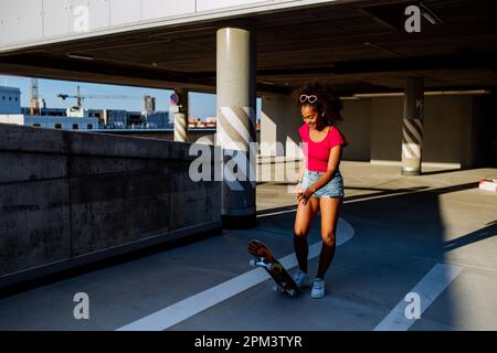 Multirassisches Teenager-Mädchen auf Skateboard in der modernen Stadt während des Sommertags. Stockfoto