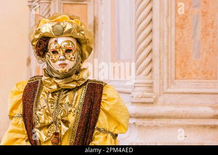 Venedig Karneval, kostümierter Teilnehmer mit Goldhut, Maske und historischem venezianischen Kleid, Venedig, Italien Stockfoto