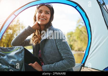 Sie entkommt allem. Eine attraktive junge Frau, die auf ihrem Campingplatz sitzt. Stockfoto