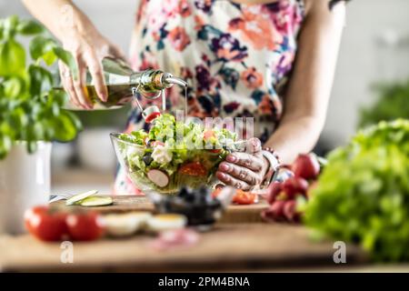 Die letzte Zubereitung eines gesunden Salats und am Ende gießt die Frau Olivenöl ein. Stockfoto