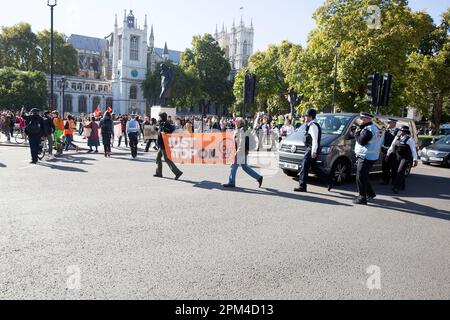 Aktivisten von „Just Stop Oil“ versuchen, ein Banner vor dem Verkehr in Westminster im Zentrum von London zu halten. Stockfoto