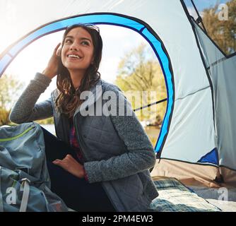 Draußen in der Wildnis ist der beste Ort zum Nachdenken. Eine attraktive junge Frau, die auf ihrem Campingplatz sitzt. Stockfoto