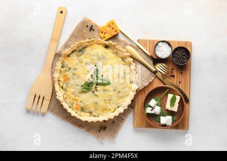 Köstliche Quiche, Butter, Fetakäse und Spinatblätter auf grauem Hintergrund Stockfoto