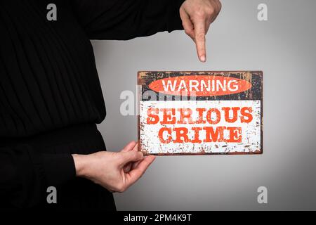 Schwerverbrechen Konzept. Warnschild mit Text auf weißem Hintergrund in der Hand einer Frau. Stockfoto