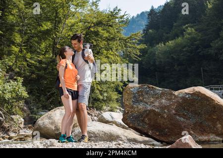 Zwei junge Wanderer, eine Frau und ein Mann genießen die wunderschöne Naturlandschaft und machen Selfie-Fotos von einer Bergkaskade Stockfoto