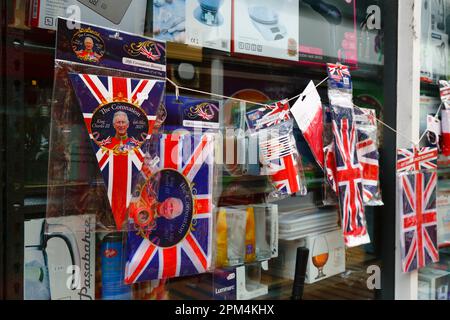 Tonbridge, Kent, 11. April 2023. Billige Union-Jack-Flaggen, Fähnchen und andere Erinnerungsstücke zur bevorstehenden Krönung von König Karl III. Zum Verkauf vor einem Eisenwarenladen. König Karl III. Wird am Samstag, den 6. Mai 2023 in Westminster Abbey in London gekrönt. Stockfoto