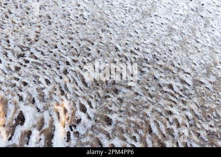 Schmelzende Eisschollen Oberfläche mit Sand, natürliche winterliche Fotostruktur Stockfoto