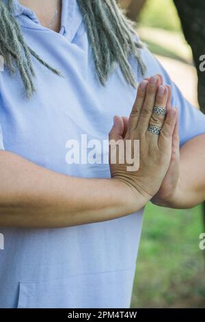 Körper einer ruhigen älteren Frau, die während des Urlaubs mit namensvollen Händen gegen die malerische Natur meditiert Stockfoto
