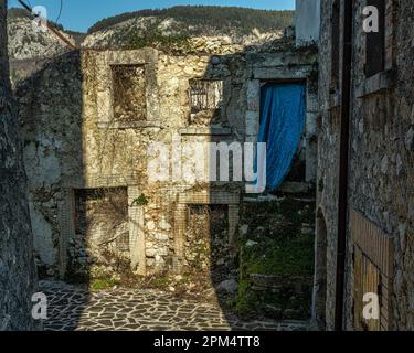 Überreste eines abgerissenen Hauses, von dem eine Wand mit Löchern in den Fenstern und Türen übrig bleibt. Schutt und Vegetation sind in das Haus eingedrungen. Abruzzen Stockfoto