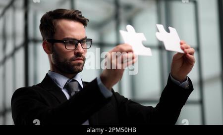 Business-Puzzle, Strategie und Marketing. Geschäftsmann zeigt silberne Teil des Puzzles Stockfoto