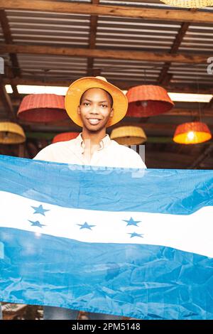 Vertikales Porträt eines jungen afroamerikanischen Mannes mit der Flagge honduras. Stockfoto