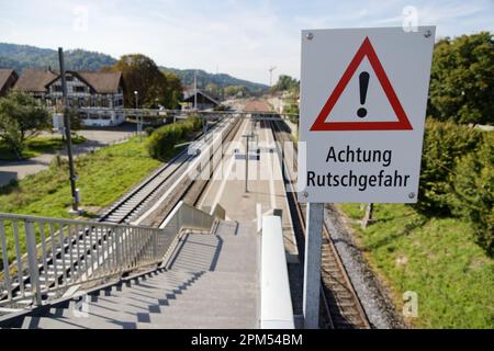 Achtung Rutschgefahr Schild vor einer Bahnhoftreppe deutsche Übersetzung: Vorsicht Rutschgefahr! Stockfoto