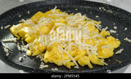 Rührei mit Käse in der Nähe einer Bratpfanne. Stockfoto