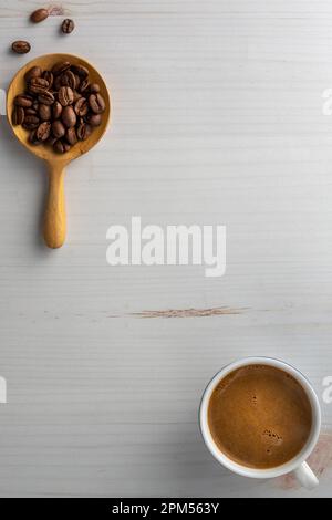 Kaffeebohnen in einem Holzlöffel und eine Tasse Kaffee. Über Schuss. Stockfoto