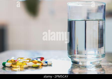Brasilien. 11. April 2023. In dieser Abbildung auf dem Tisch neben einem Glas Wasser mehrere Pillen. (Kreditbild: © Rafael Henrique/SOPA Images via ZUMA Press Wire) NUR REDAKTIONELLE VERWENDUNG! Nicht für den kommerziellen GEBRAUCH! Stockfoto