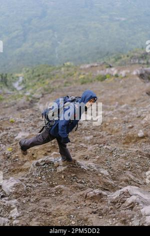 Ein Mann in den Bergen steigt auf einen Berg, steigt von einem Berg ab Stockfoto