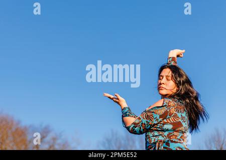 Leidenschaftliches Porträt einer Frau, die gegen den blauen Himmel tanzt Stockfoto