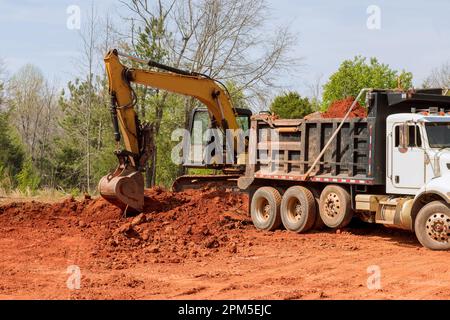 Die Erde wird von einem Bagger in den Muldenkipper geladen Stockfoto