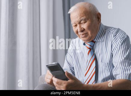 Senior Mann trägt formelle Kleidung und benutzt Smartphone Stockfoto