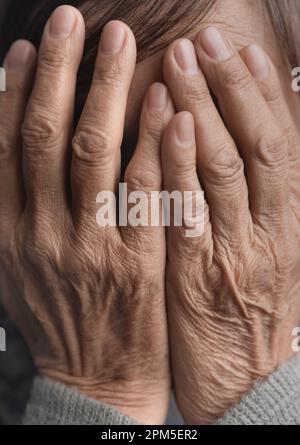 Deprimierte und frustrierte ältere Frau mit Händen, die sein Gesicht bedecken Stockfoto