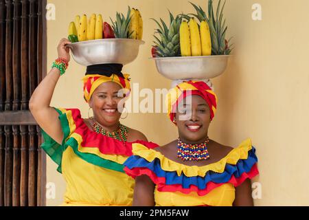 Fröhliche lächelnde Straßenverkäufer von frischem Obst aus Palenquera in der Altstadt von Cartagena, Kolumbien. Fröhliche afrokolumbianische Frauen in traditionellen Kostümen. Stockfoto