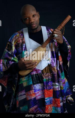 Afrikanischer Musiker mit Saiteninstrument und typischer Kleidung. Stockfoto